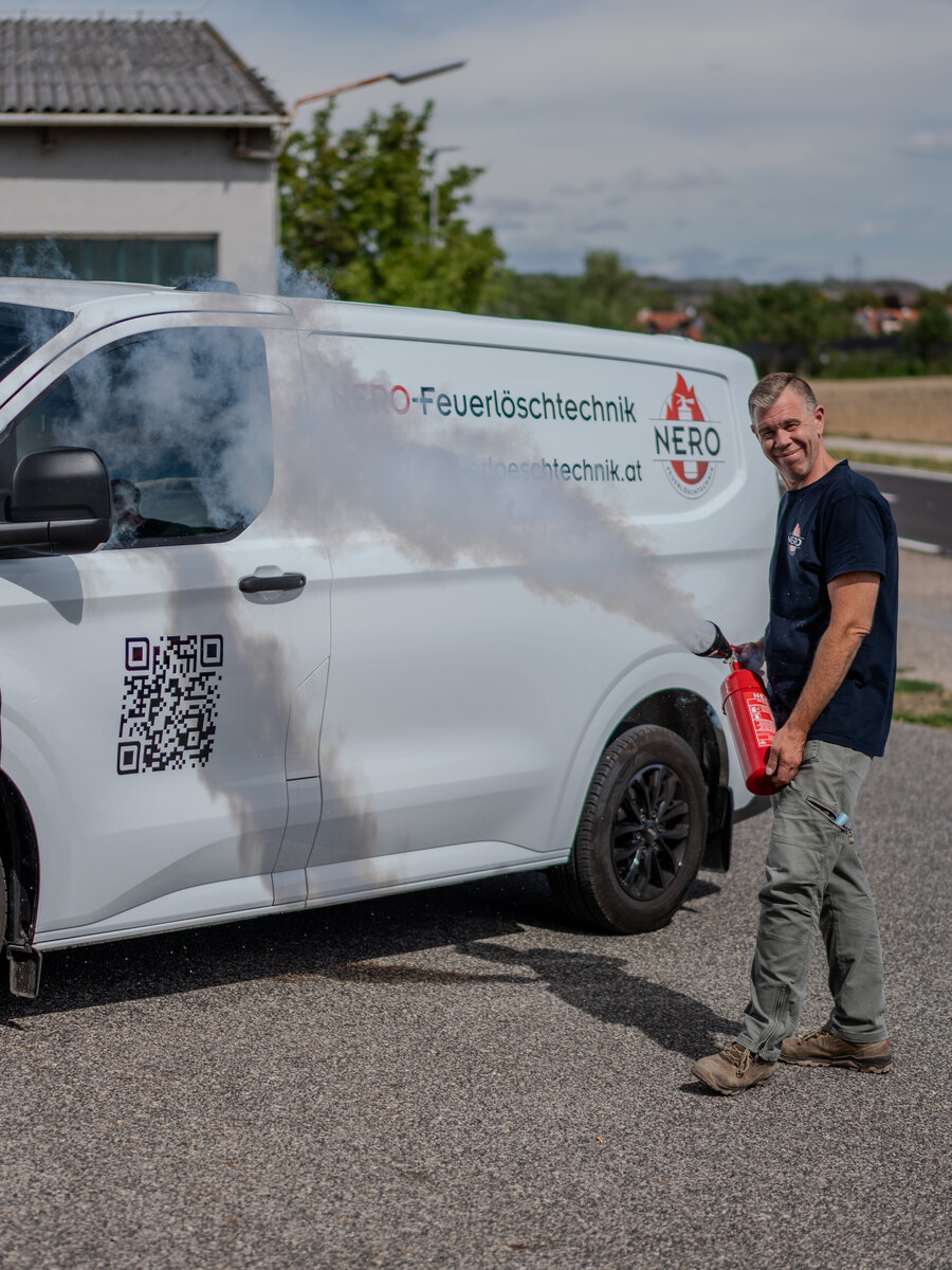Christian Urbanek von NERO Feuerlöschtechnik bei einer Löschvorführung vor dem Firmenfahrzeug